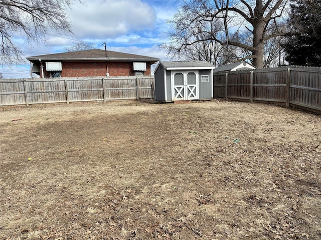 view of yard with a storage shed, a fenced backyard, and an outbuilding