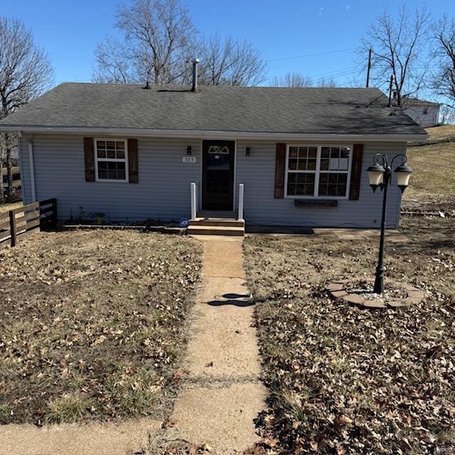 single story home featuring roof with shingles and fence