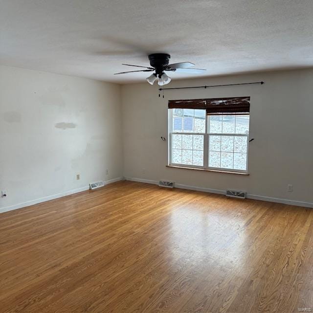 unfurnished room featuring visible vents, ceiling fan, baseboards, and wood finished floors