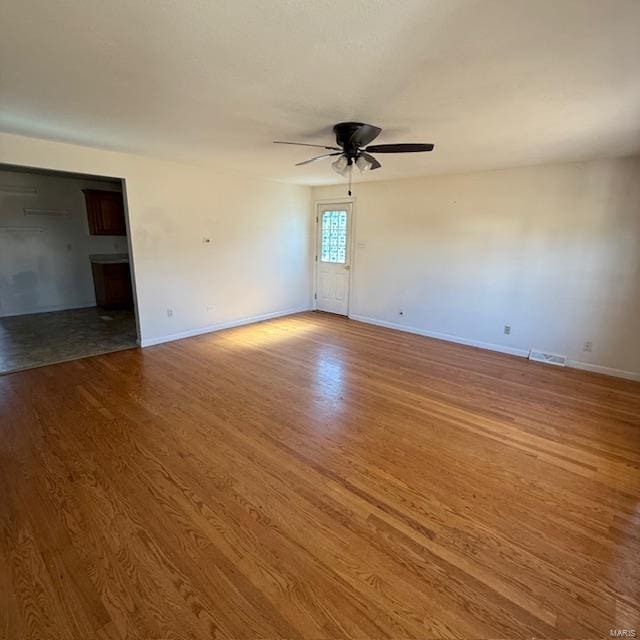 interior space featuring baseboards, ceiling fan, visible vents, and wood finished floors