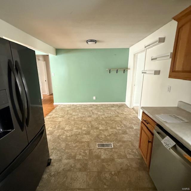 kitchen featuring black fridge with ice dispenser, visible vents, baseboards, dishwasher, and brown cabinetry