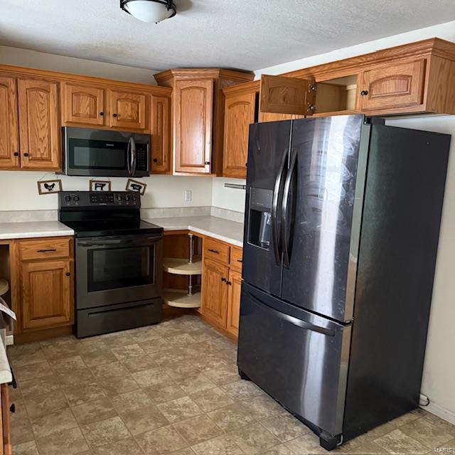 kitchen with brown cabinetry, light countertops, and black appliances