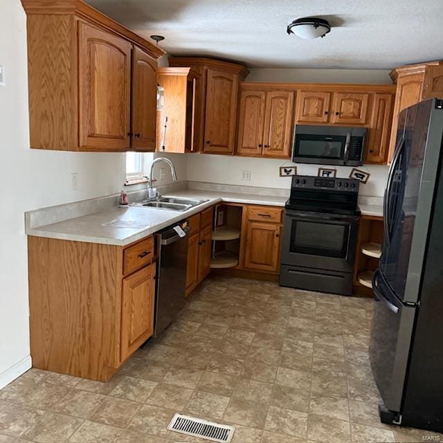 kitchen featuring light countertops, visible vents, a sink, and black appliances