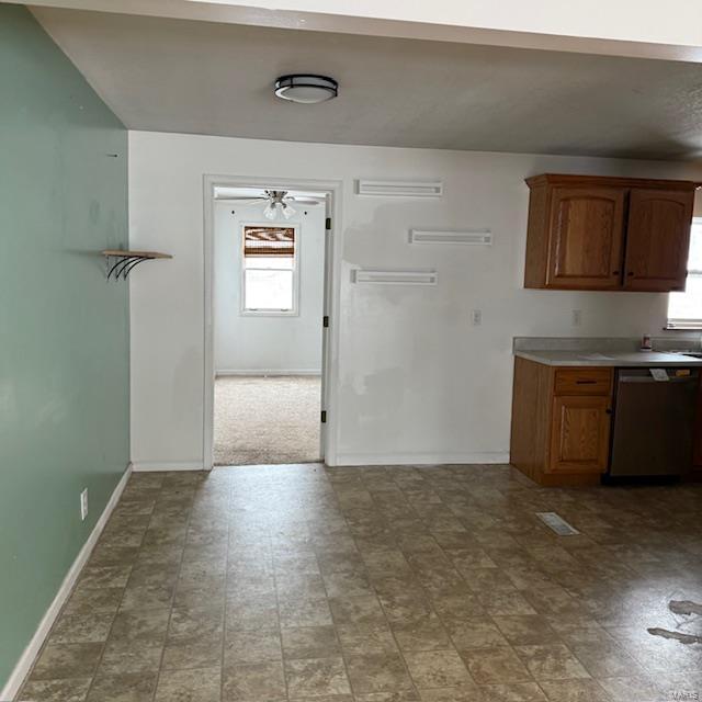 kitchen with baseboards, brown cabinetry, a ceiling fan, light countertops, and stainless steel dishwasher