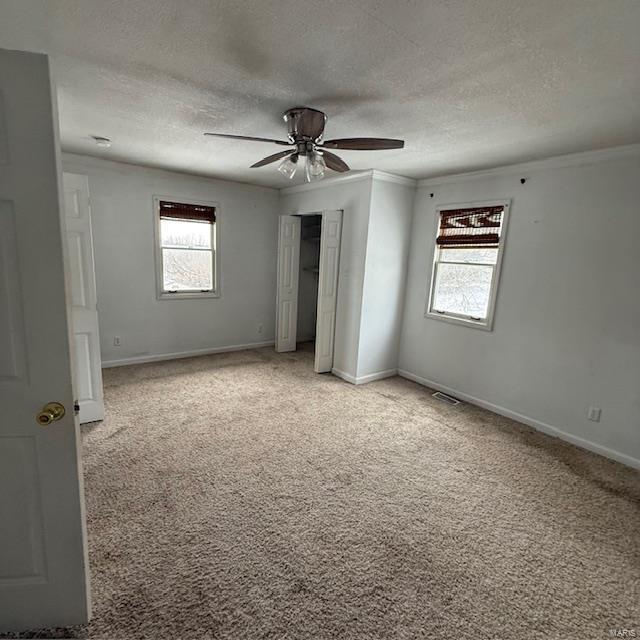 unfurnished bedroom featuring ornamental molding, light carpet, visible vents, and multiple windows