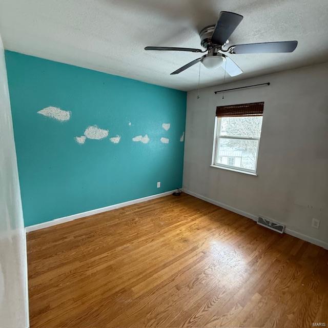 spare room with baseboards, a textured ceiling, visible vents, and wood finished floors