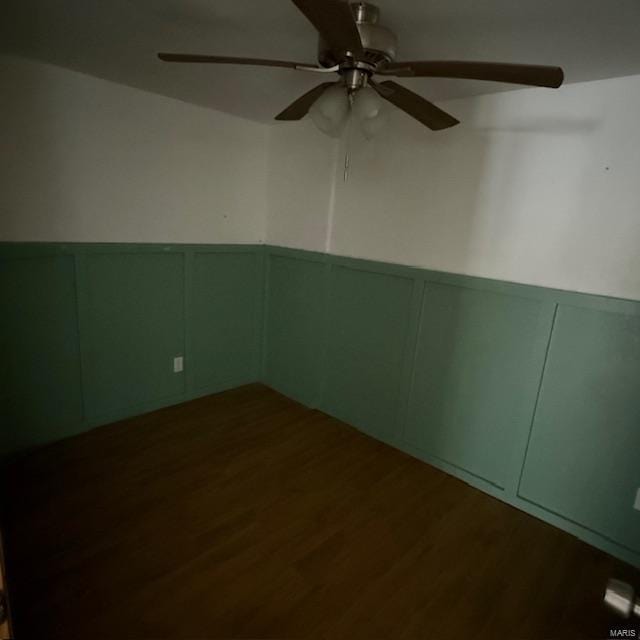 unfurnished room featuring wainscoting, a decorative wall, and wood finished floors