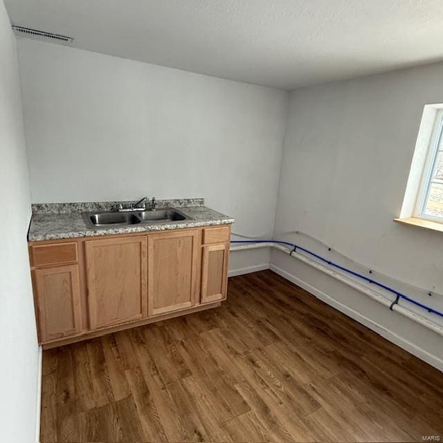 kitchen with baseboards, visible vents, dark wood finished floors, and a sink