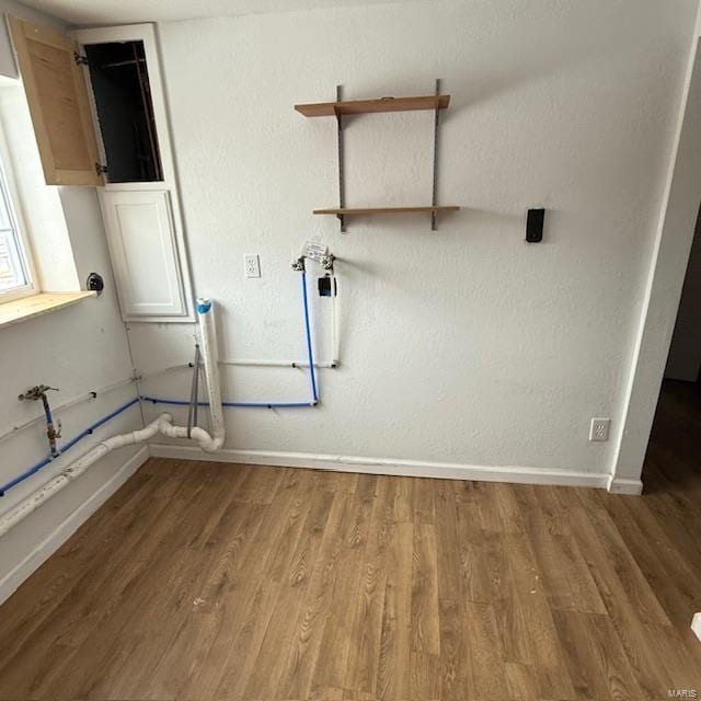 laundry area featuring baseboards and wood finished floors