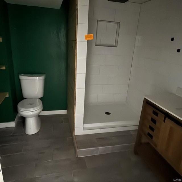 full bath featuring toilet, baseboards, and tiled shower