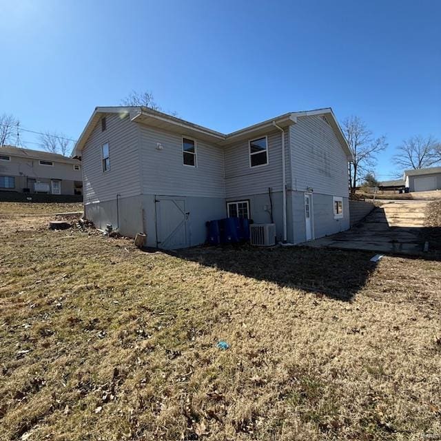 rear view of house featuring cooling unit and a yard