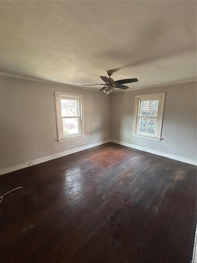 spare room featuring crown molding, dark wood-type flooring, a ceiling fan, and baseboards