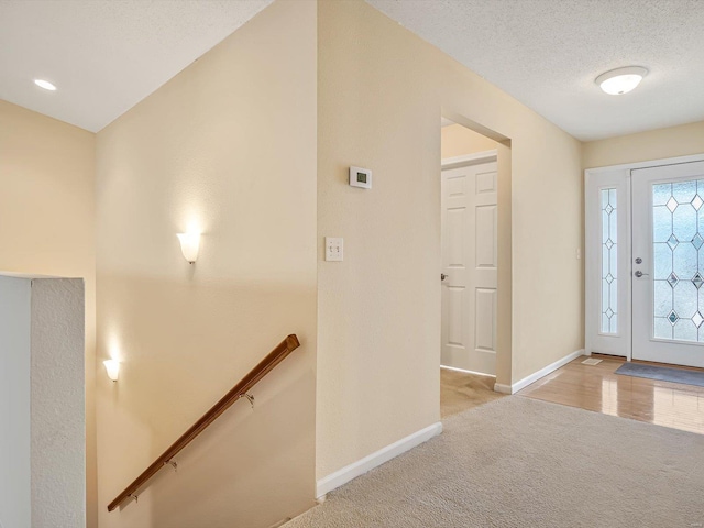 carpeted entrance foyer featuring a textured ceiling and baseboards