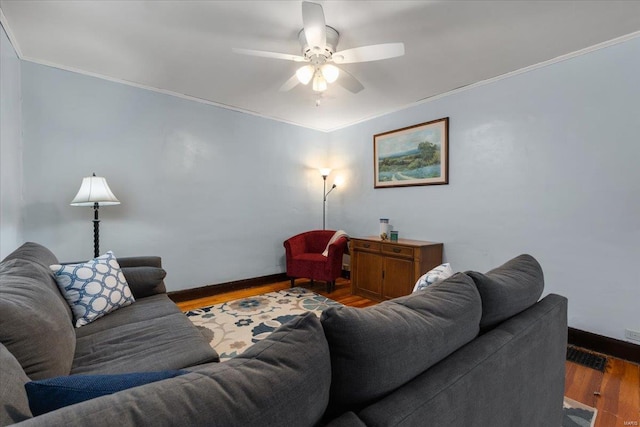 living area featuring visible vents, baseboards, a ceiling fan, ornamental molding, and wood finished floors