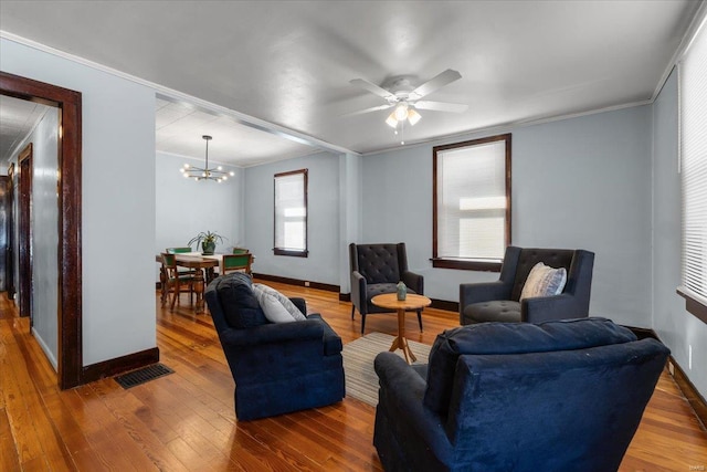 living area with baseboards, crown molding, visible vents, and wood finished floors