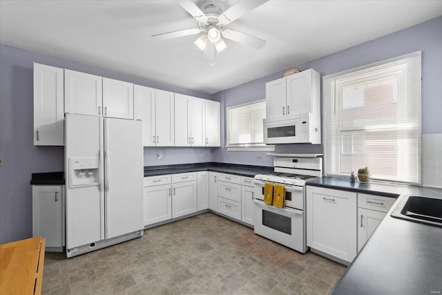 kitchen featuring white appliances, white cabinets, and plenty of natural light