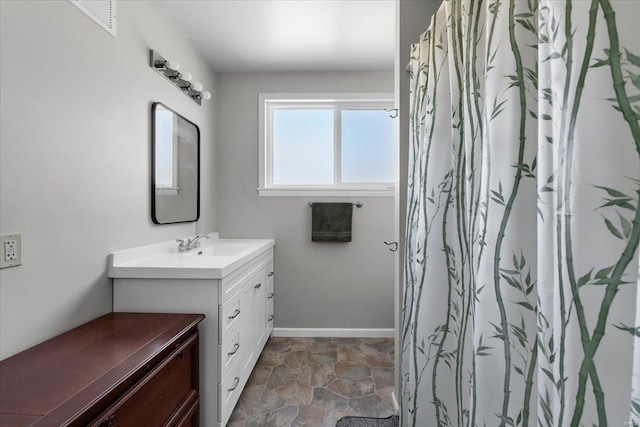 full bath with stone finish flooring, baseboards, and vanity