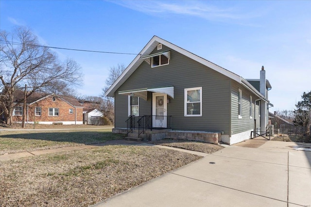 bungalow-style home with a chimney and a front yard