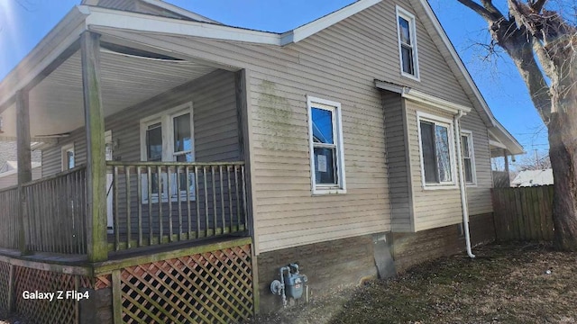 view of side of home with covered porch and fence