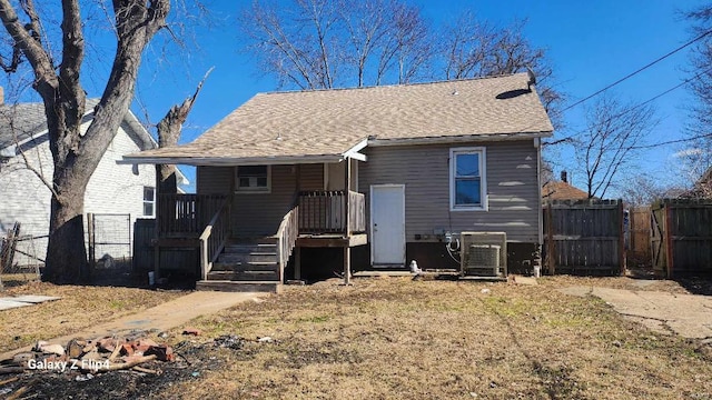 back of property featuring a shingled roof, fence, and central AC