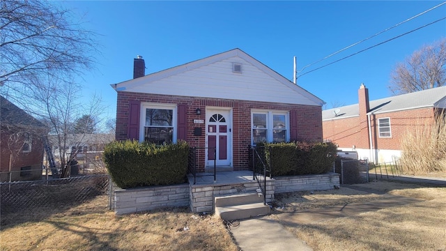 view of front of property featuring brick siding, fence, and a chimney