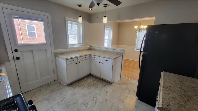 kitchen featuring freestanding refrigerator, a peninsula, marble finish floor, light countertops, and white cabinetry