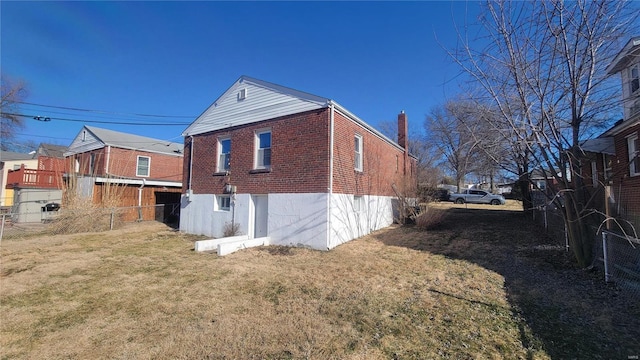 view of side of home with brick siding, a yard, and fence