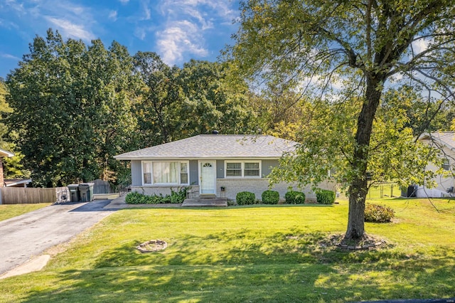 view of front facade with a front yard, brick siding, driveway, and fence