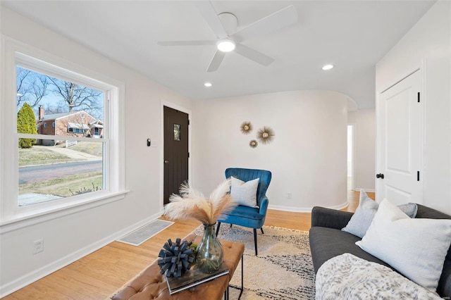 living room featuring light wood-style flooring, baseboards, and visible vents