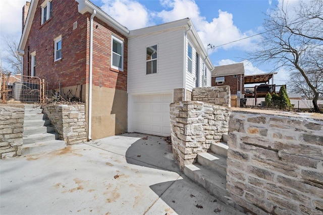 view of side of property featuring brick siding, an attached garage, and driveway