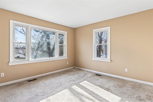 carpeted spare room with visible vents and baseboards