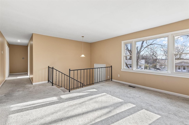 carpeted empty room featuring baseboards and visible vents