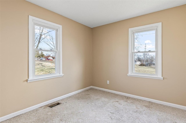 unfurnished room featuring a healthy amount of sunlight, baseboards, visible vents, and carpet flooring