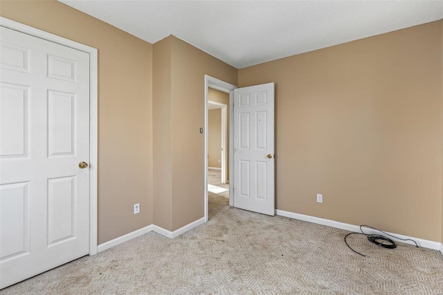 unfurnished bedroom with light colored carpet and baseboards