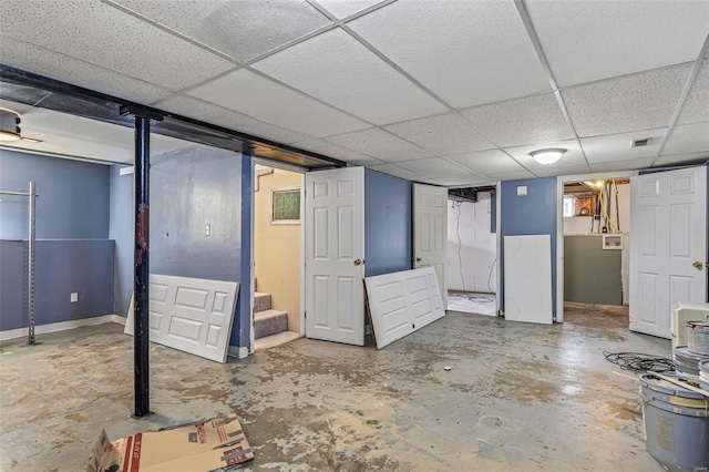 finished basement featuring visible vents, stairway, a paneled ceiling, and baseboards