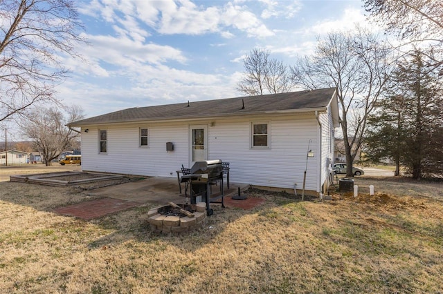 back of house with an outdoor fire pit, a patio area, and a lawn