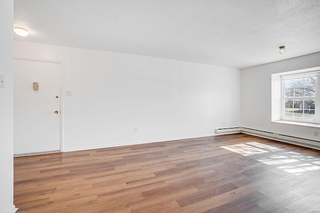 spare room with baseboards, a textured ceiling, and wood finished floors