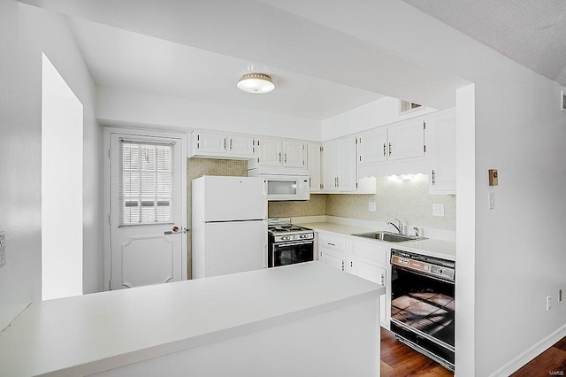 kitchen featuring a sink, dark wood finished floors, white cabinetry, white appliances, and light countertops