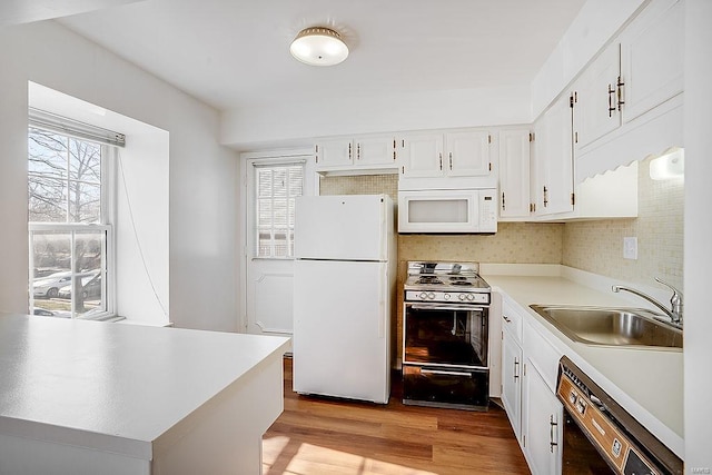 kitchen featuring light wood finished floors, light countertops, white cabinets, white appliances, and a sink