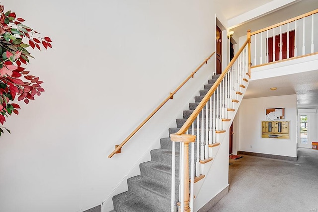 stairway featuring baseboards and a towering ceiling