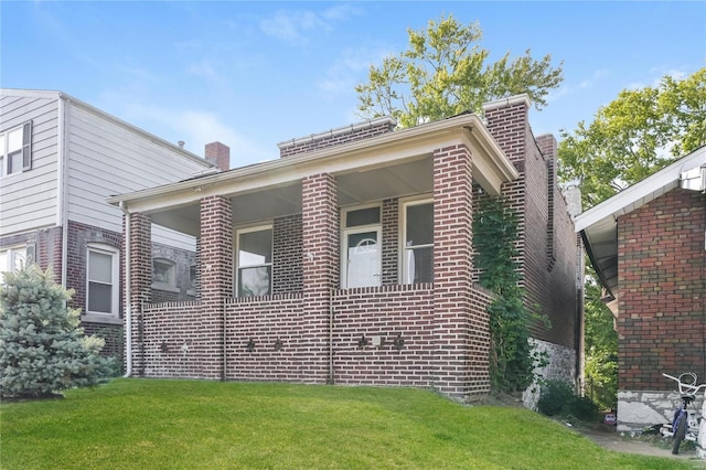 view of side of home with brick siding, a chimney, and a yard