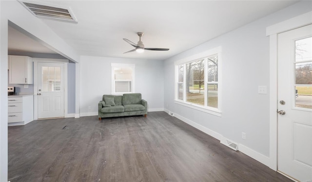 unfurnished room featuring baseboards, visible vents, dark wood finished floors, and a ceiling fan