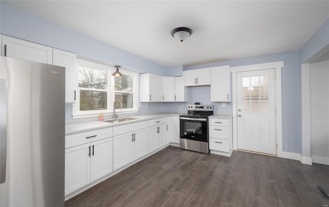 kitchen featuring dark wood-type flooring, a sink, white cabinetry, light countertops, and appliances with stainless steel finishes