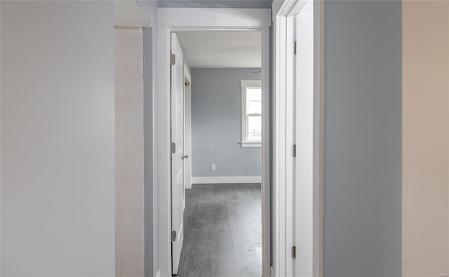 corridor featuring dark wood-style flooring and baseboards