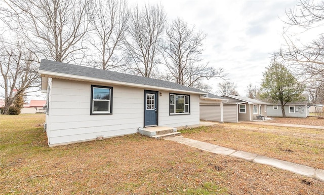 ranch-style home with a front lawn and roof with shingles