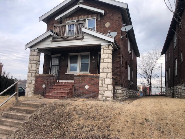 view of front facade featuring a porch, a balcony, and brick siding