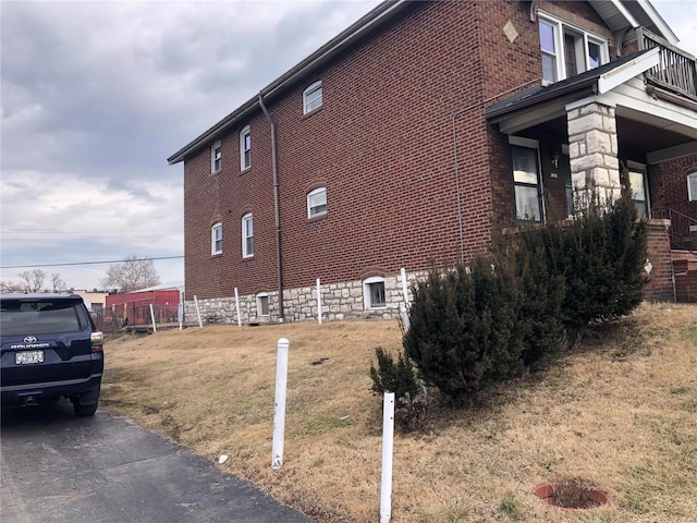 view of side of home featuring brick siding and a yard