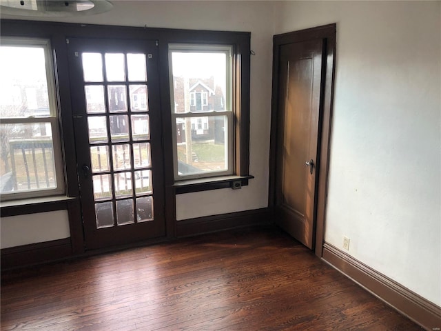 empty room featuring dark wood-type flooring, plenty of natural light, and baseboards