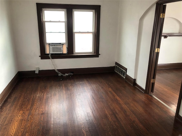 spare room with visible vents, baseboards, dark wood-type flooring, and cooling unit