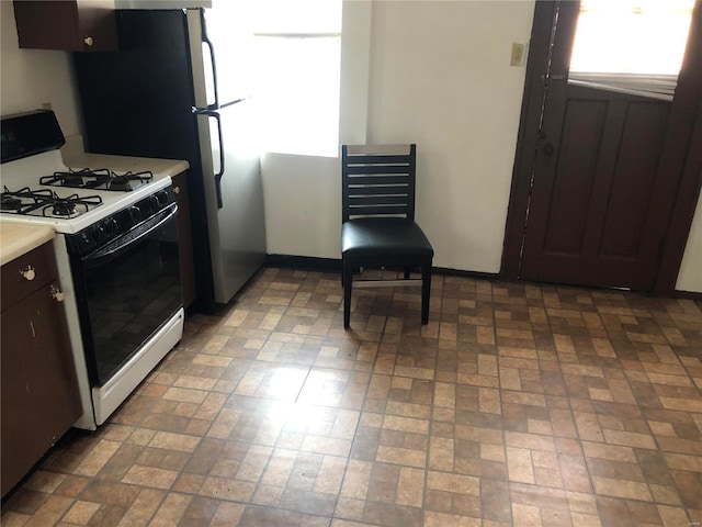 kitchen featuring light countertops, gas range oven, and brick floor